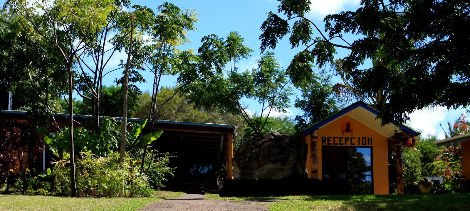 Resort-style buildings and pool near tropical planting.